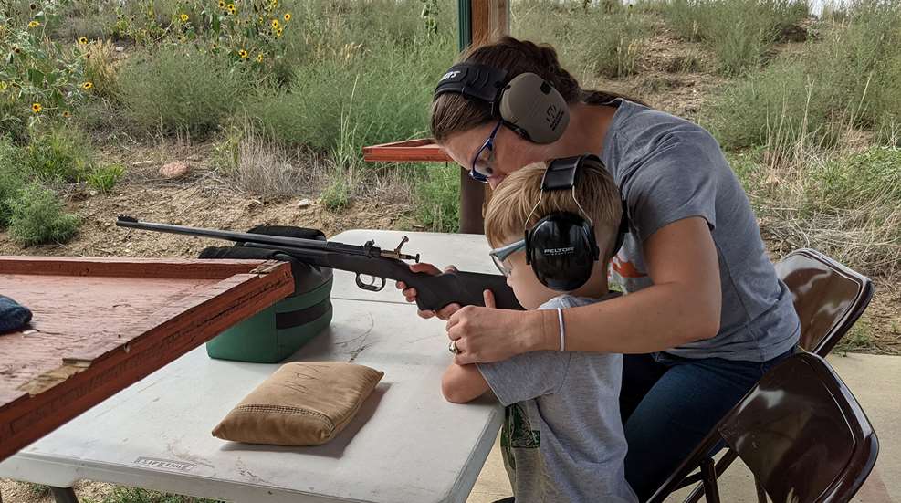 A woman and child with headphones holding guns.