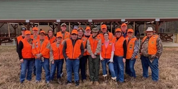 A group of people in orange vests standing next to each other.