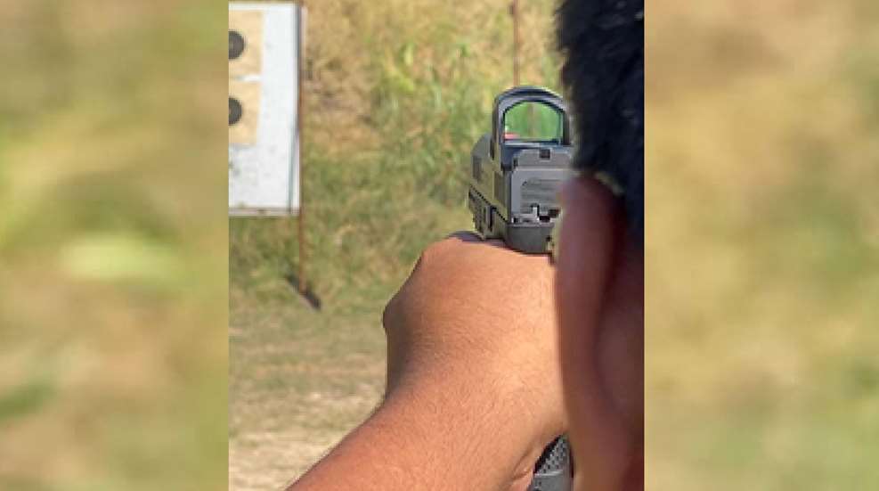 A person holding a gun with a sight on it.
