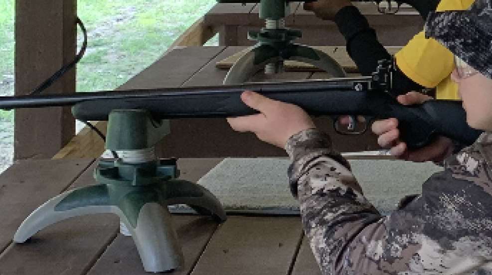 A person holding on to the end of a rifle