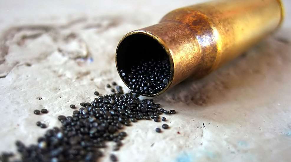 A close up of a bullet casing with black beads