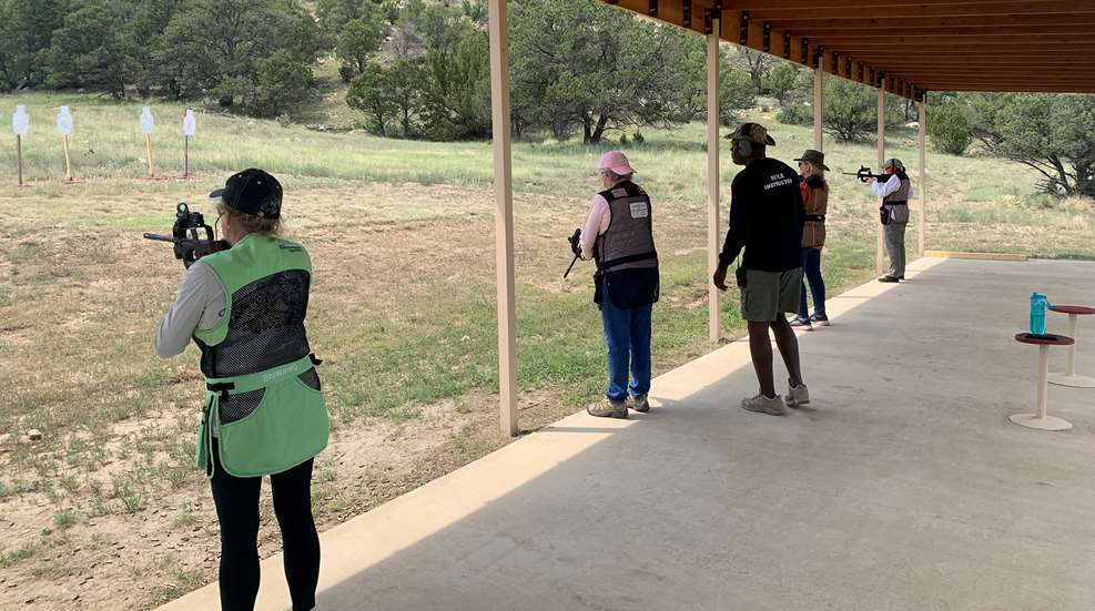 A group of people standing around at the shooting range.