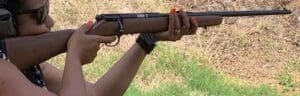 A woman holding on to the end of a rifle.