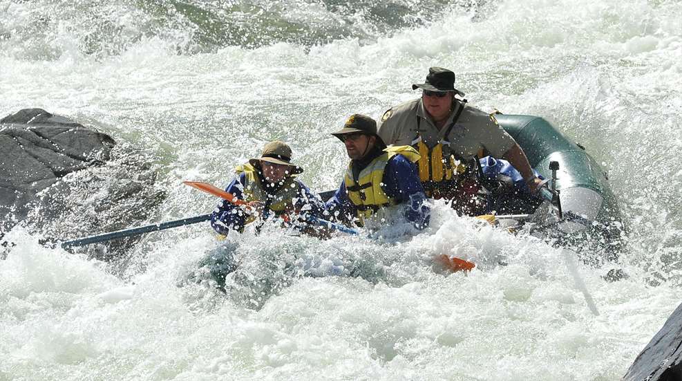 Three people are in a raft on the water.