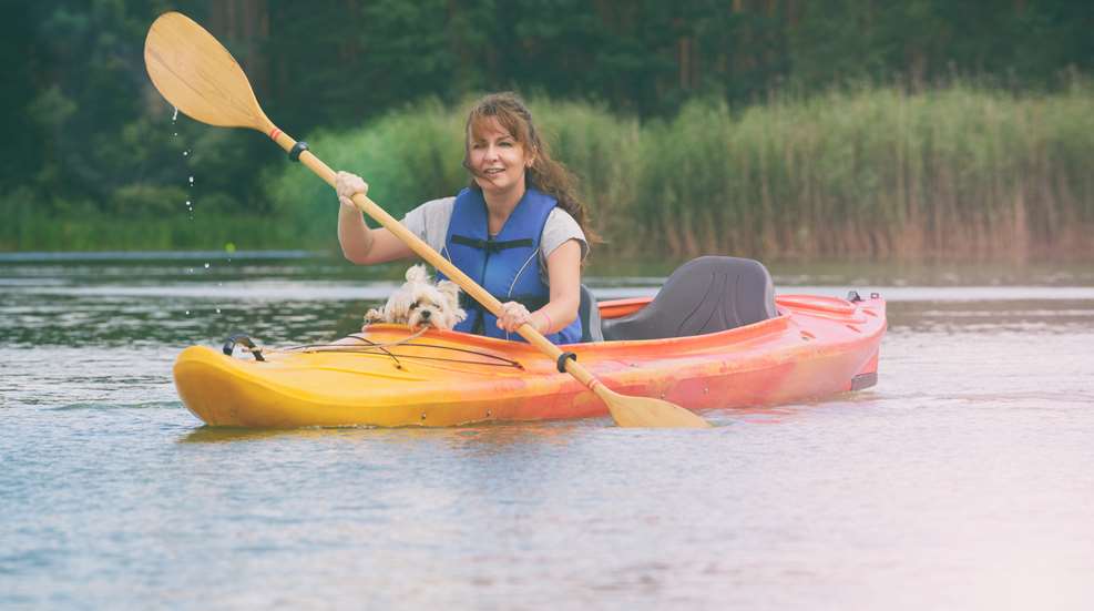 A woman is kayaking with her dog in the water.
