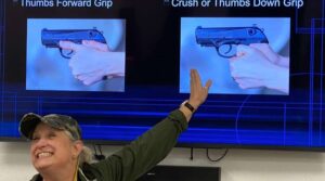 A woman pointing to two pictures of guns.