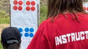 A woman in red shirt standing next to a target.