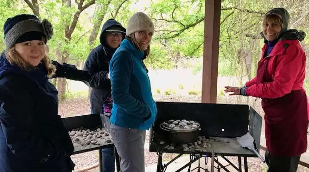 Man cooking with a campfire outdoors.