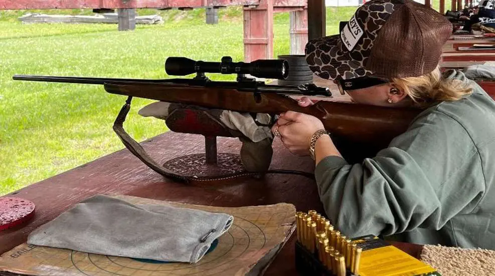 Hunter preparing rifle in outdoor setting.
