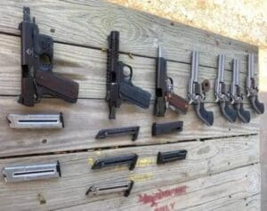 Various disassembled firearms and components laid out on wooden surface.