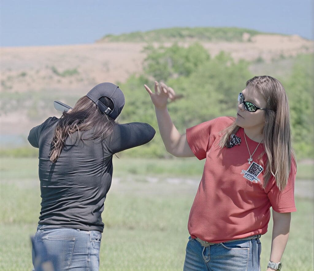 Two people practicing disc golf outdoors.